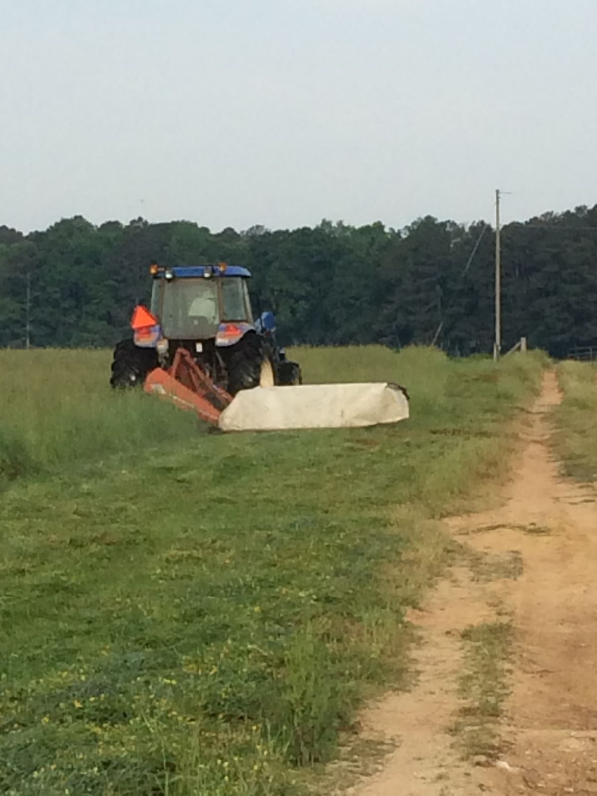 New Holland tractor mowing hay on the family farm in Cave Spring, Georgia