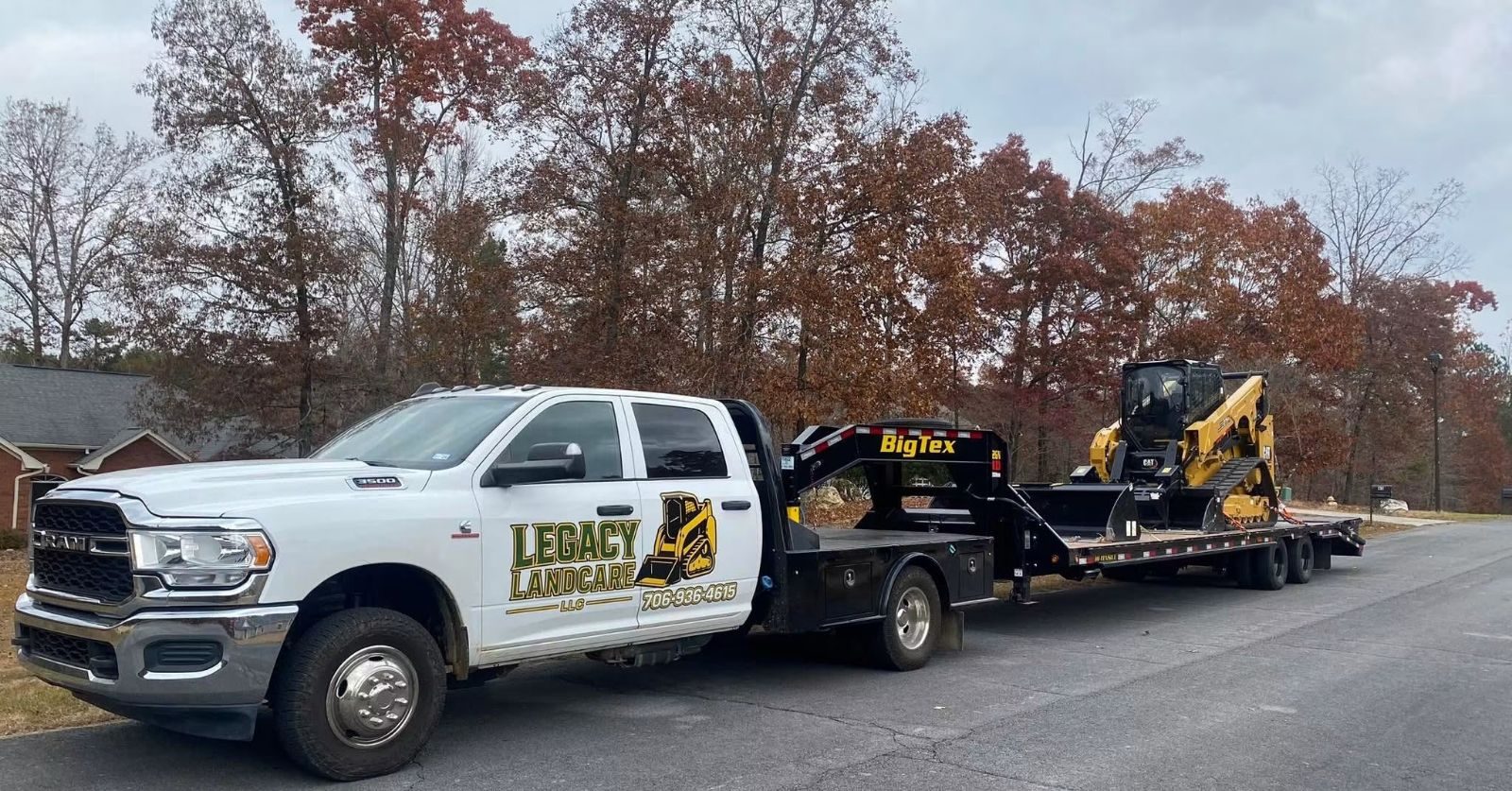 Legacy Land Care truck hauling a CAT compact track loader on a gooseneck trailer in Northwest Georgia
