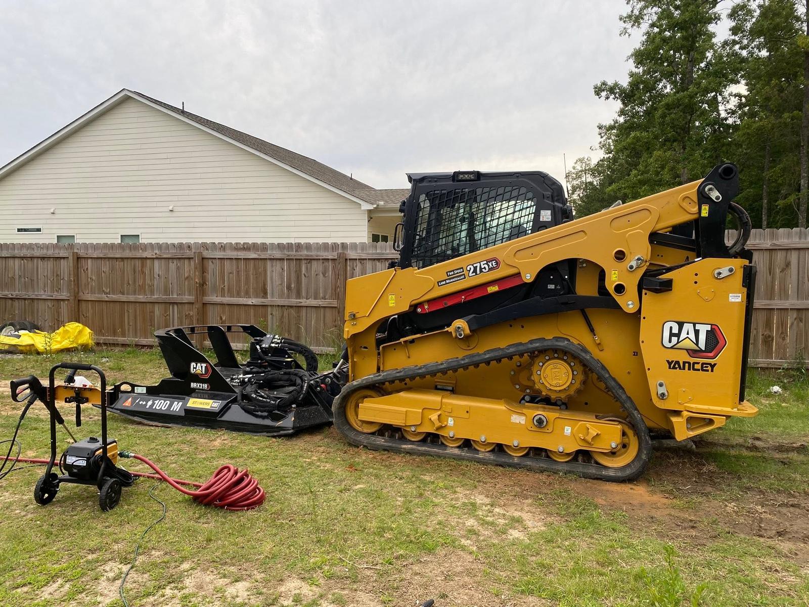CAT track loader with grading bucket and attachments at a job site